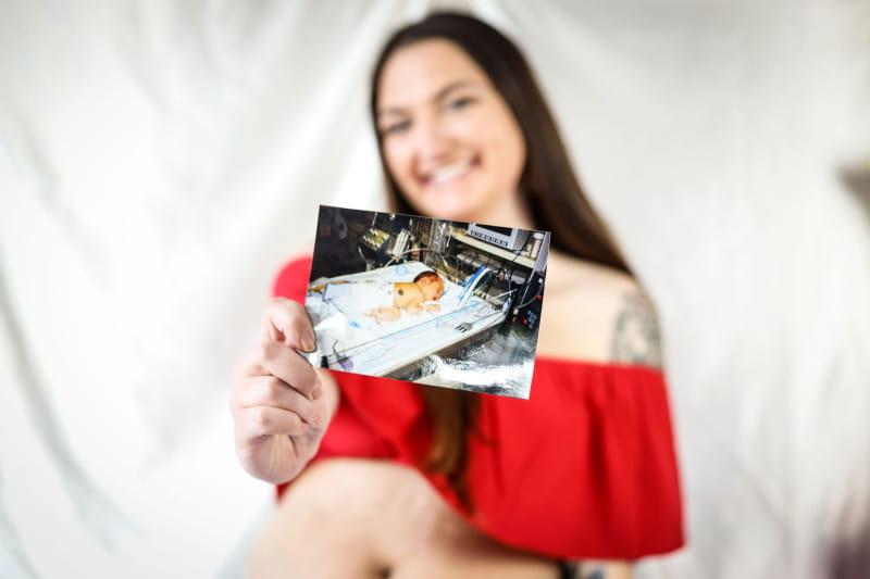 Micky Foos holding a picture of herself as a baby. (Photo courtesy of Paytience Rose Photography)